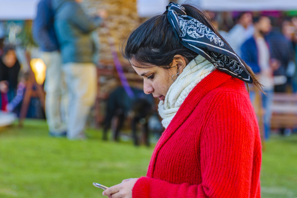Young woman watching her cellphone at urban outdoor street fair, montevideo city, uruguay